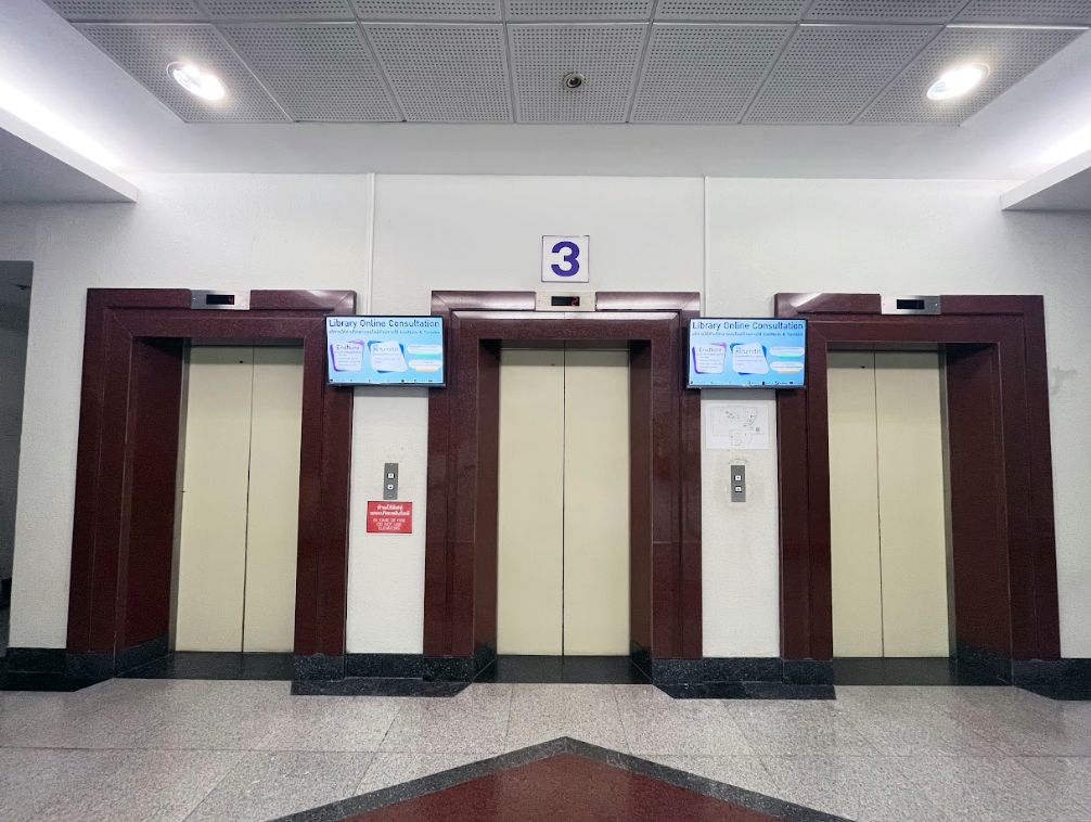 Two elevator lobby screens on the third floor display the library fine waiver campaign, complete with a QR code students can scan on the spot.