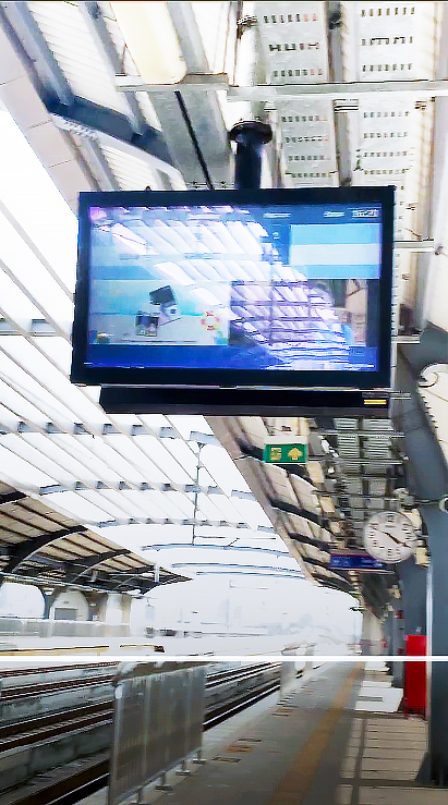 A CAYIN SMP-2200 powered screen mounted at a Red Line station, running alongside the station clock.