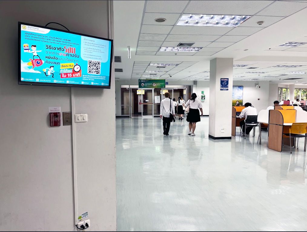 カセサート大学図書館の 3 階、エレベーターの扉の上に設置されたデジタルサイネージ。階を移動する際に待つすべての学生の目に届く。